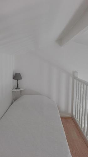 a white bed in a white room with a lamp at L'auberge Camarguaise in Saintes-Maries-de-la-Mer