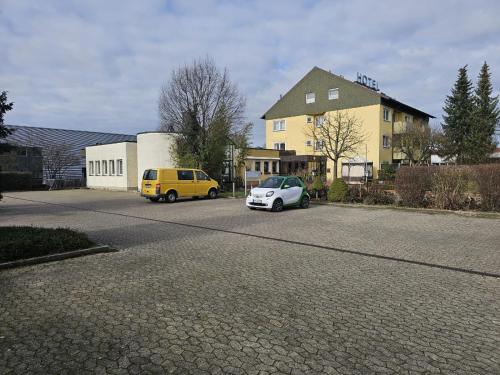 two cars parked in a parking lot next to a building at Hotel Tennenloher Hof in Erlangen