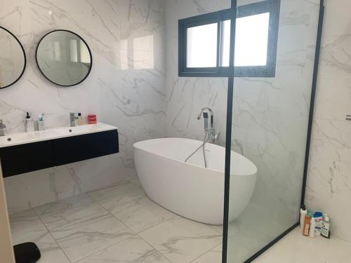 La salle de bains blanche est pourvue d'une baignoire et d'un lavabo. dans l'établissement Villa contemporaine avec piscine et grand jardin, à Bernis