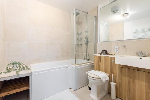 a bathroom with a tub and a toilet and a sink at The Clapham Terraced House in London