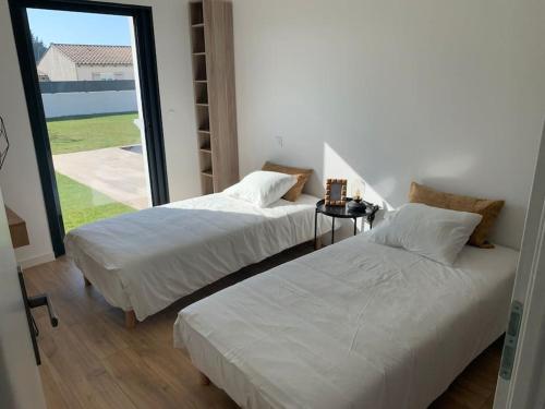 Duas camas num quarto com uma janela grande em Villa contemporaine avec piscine et grand jardin em Bernis