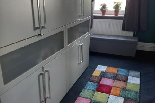 a kitchen with white cabinets and a colorful rug at Private Apartment Smoker in Hannover