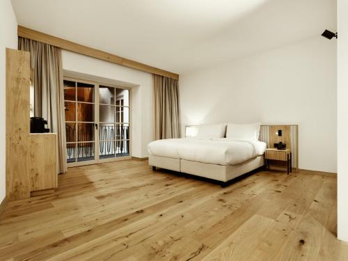 a bedroom with a white bed and wooden floors at ADLER Historic Guesthouse in Bressanone
