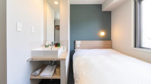 a small bedroom with a bed and a sink at Super Hotel Fujikawaguchiko Tennenonsen in Fujikawaguchiko