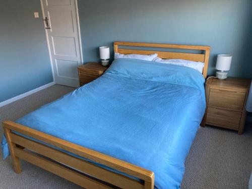a bedroom with a large bed with a blue comforter at Cosy at Cumberland - Double room with shared bathroom in Dundonald