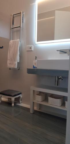 a bathroom with a sink and a mirror and a shelf at Appartamento Rapallo Sky Garden Maria Jose Liguria - Attico vista mare - Terraces - 2 bagni- 2 Camera da Letto - Box, Wi-fi, Idromassaggio Free inteiro Attico per Voi, con Ascensore in Rapallo