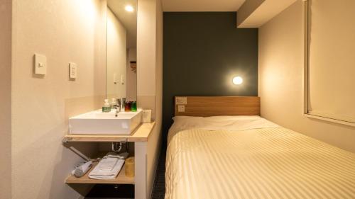 a small bedroom with a bed and a sink at Super Hotel Fujikawaguchiko Tennenonsen in Fujikawaguchiko