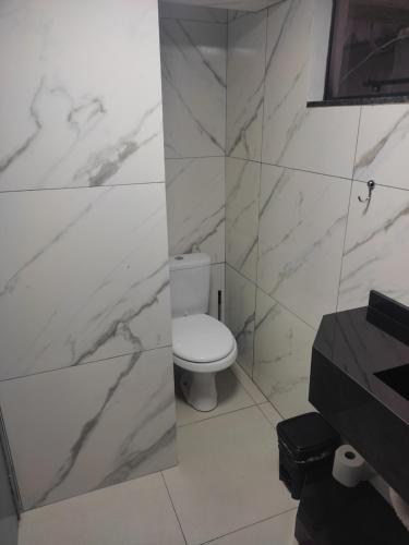 La salle de bains est pourvue de toilettes blanches et de murs en marbre. dans l'établissement Apartamento Central, à Ametista do Sul