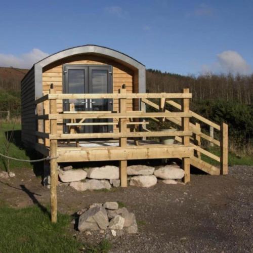 a small wooden cabin with a fence and rocks at The Peregrine - 2 Person Luxury Glamping Cabin in Dungarvan