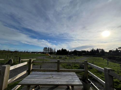 un tavolo da picnic in legno in un campo con recinzione di The Peregrine - 2 Person Luxury Glamping Cabin a Dungarvan