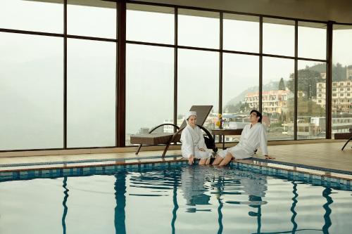 two women in white robes sitting next to a swimming pool at Amazing Hotel Sapa in Sa Pa