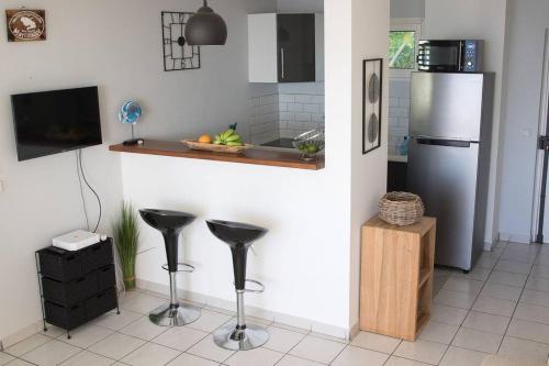 eine Küche mit einem Kühlschrank aus Edelstahl und Hockern in der Unterkunft T3 résidence les ramiers (anse a l'âne) in Les Trois-Îlets