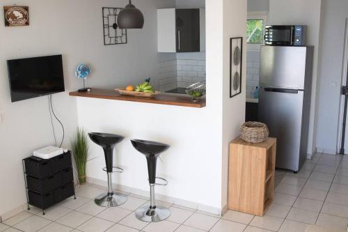 una cucina con frigorifero e sgabelli in acciaio inossidabile di T3 résidence les ramiers (anse a l'âne) a Les Trois-Îlets