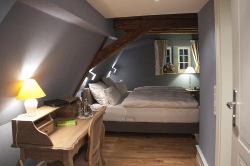 a bedroom with a bed and a desk with a desk sidx sidx sidx at Weinhotel Eltvinum in Eltville
