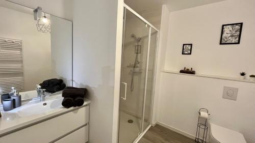 een witte badkamer met een wastafel en een douche bij La Bri'Z de Dinard in Dinard