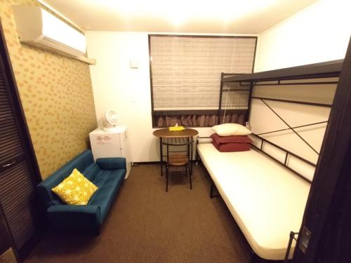 沖縄市にあるGuesthome Machiya Kozaの二段ベッドとテーブルが備わる小さな客室です。