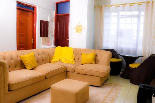 a living room with a brown couch with yellow pillows at Kay homes in Nairobi