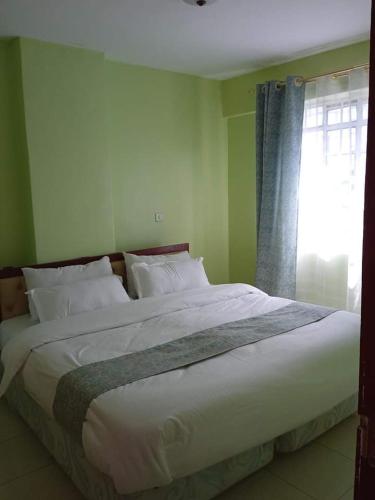 a large bed in a bedroom with a window at Kay homes in Nairobi