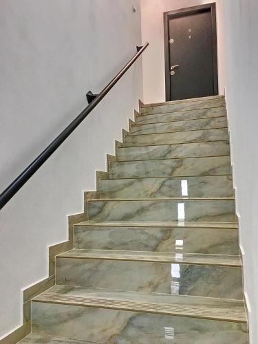 uma escada com pisos em mármore e uma porta preta em Casa Bozi em Utvin