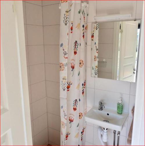 a bathroom with a sink and a shower curtain with flowers at Lunagården in Åhus