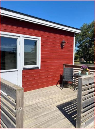 a red building with a wooden deck with a bench at Lunagården in Åhus