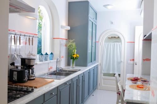 a kitchen with blue cabinets and a sink at Villa Edlin in Praiano