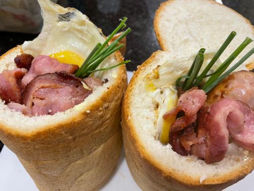 two hot dogs on a plate with cheese and bacon at Modjadji Estate Lodge & Spa in Grietjie Nature Reserve