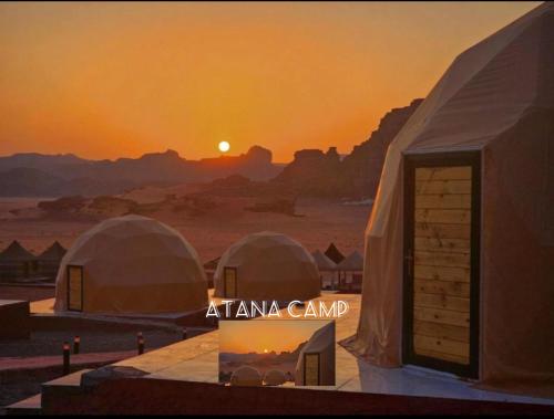 RUM ATANA lUXURY CAMP في وادي رم: اطلالة على صحراء مع خيام امام غروب الشمس