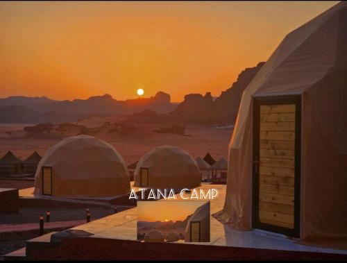a view of a desert with tents in front of the sunset at RUM ATANA lUXURY CAMP in Wadi Rum
