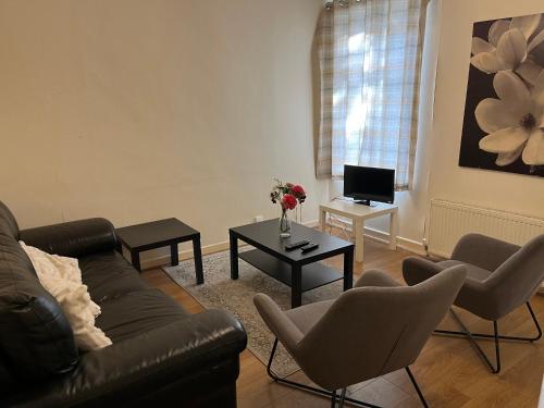 a living room with a couch and chairs and a table at Villa Parrin in Manchester