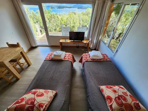 two beds in a room with a large window at Punta Negra in Villa Pehuenia