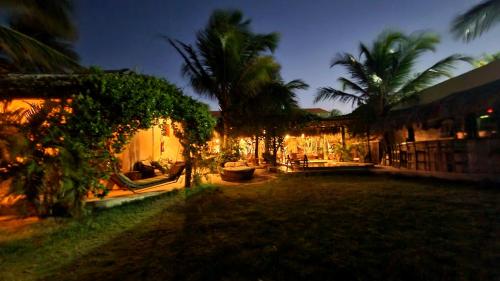 un patio con palmeras y una casa por la noche en Coco-Knots Kite - Ilha do Guajiru en Itarema