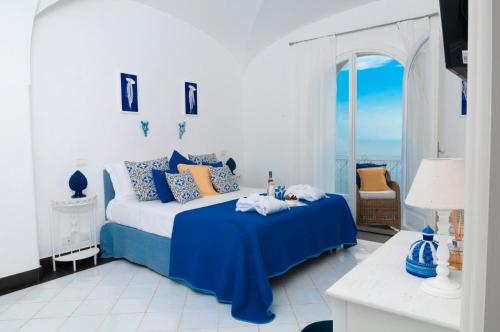 a blue and white bedroom with a bed and a window at Villa Edlin in Praiano