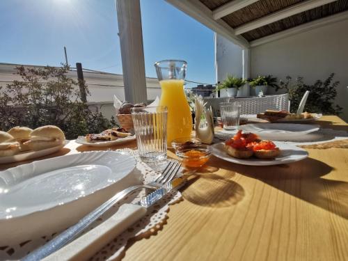 a wooden table with plates of food and orange juice at Carpe Diem B&B e Case Vacanza in Monopoli
