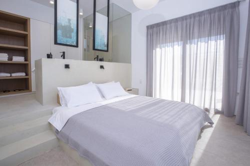 a white bedroom with a large bed and a window at ELYANE VILLAS near AMMOUSSA BEACH in Évyiros