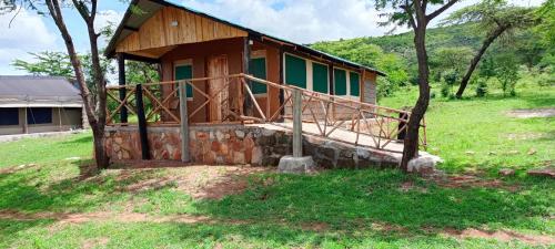 una piccola casa su una collina erbosa con un albero di orkaria safari mara camp a Sekenani