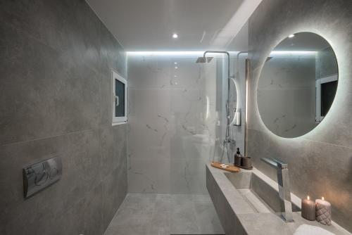 a bathroom with a shower with a round mirror at Central 2 Bdrm Aprt In Koukaki! in Athens