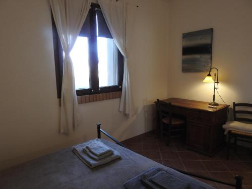 a bedroom with a bed and a desk and a window at Poggio la Luna - La casa nel vigneto in Montemerano