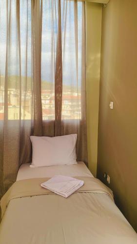 uma cama com uma janela com uma toalha em City view apartments 1 em Serres