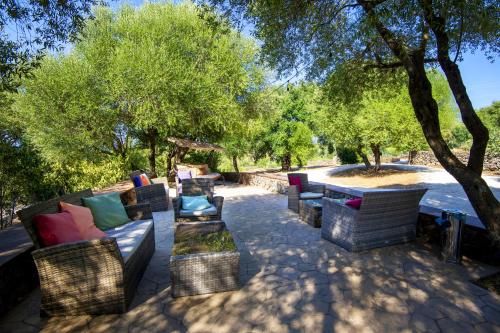 a group of wicker chairs and tables under a tree at Hotel Barbagia in Dorgali