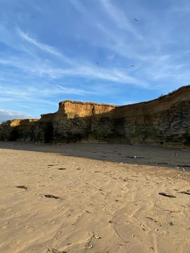 une plage de sable à côté d'une falaise rocheuse dans l'établissement ALAMER, à Lion-sur-Mer