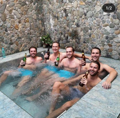 un grupo de hombres bebiendo cerveza en una piscina en Hostal Chimenea, en Baños