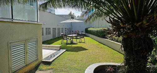 a backyard with a table and chairs and a palm tree at Option Full Service Residence in Rio de Janeiro