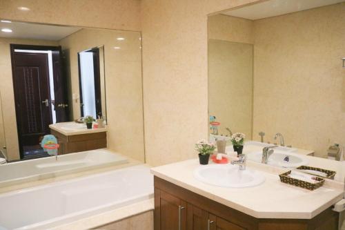 een badkamer met een bad, een wastafel, een bad en een spiegel bij Vinhomes Royal City#3BR Serviced Apartment in Hanoi