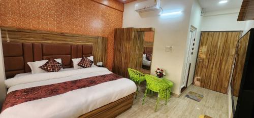 een slaapkamer met een groot bed en een groene stoel bij jsb hotel in Kakarmatha