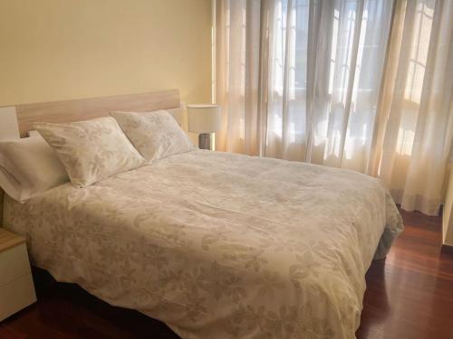 a bedroom with a bed with white sheets and a window at El apartamento de Adriana en Torrelavega. in Torrelavega