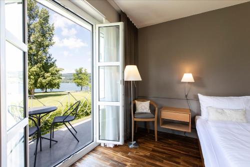 a bedroom with a bed and a large window at See & Park Hotel Feldbach in Steckborn