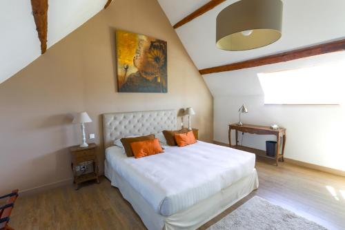 sypialnia z dużym białym łóżkiem z pomarańczowymi poduszkami w obiekcie La Villa Bel Air w mieście Flamanville