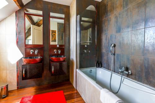 a bathroom with two red sinks and a tub at La Villa Bel Air in Flamanville