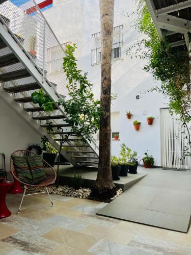 a room with stairs and a chair next to a tree at Chipibeach B&B, Hostal Boutique in Chipiona